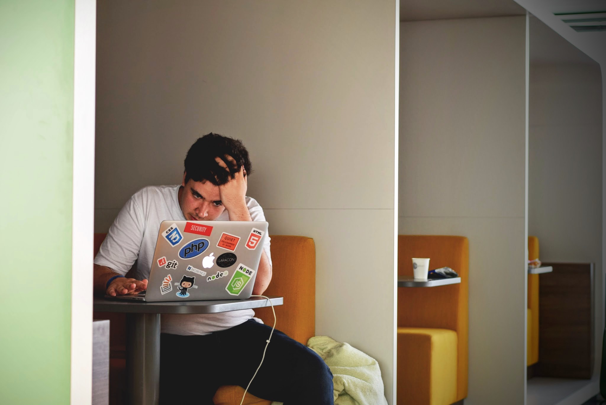 Informatiker sitzt an einem Laptop mit Aufklebern verschiedener IT-Projekte