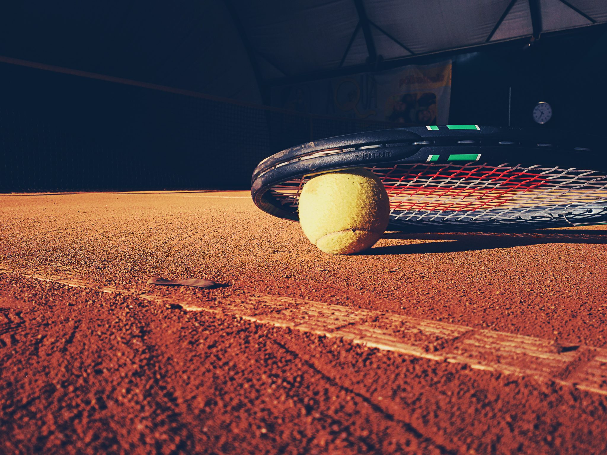 Tennisschläger liegt mit einem Tennisball auf dem Boden eines Tennisplatzes